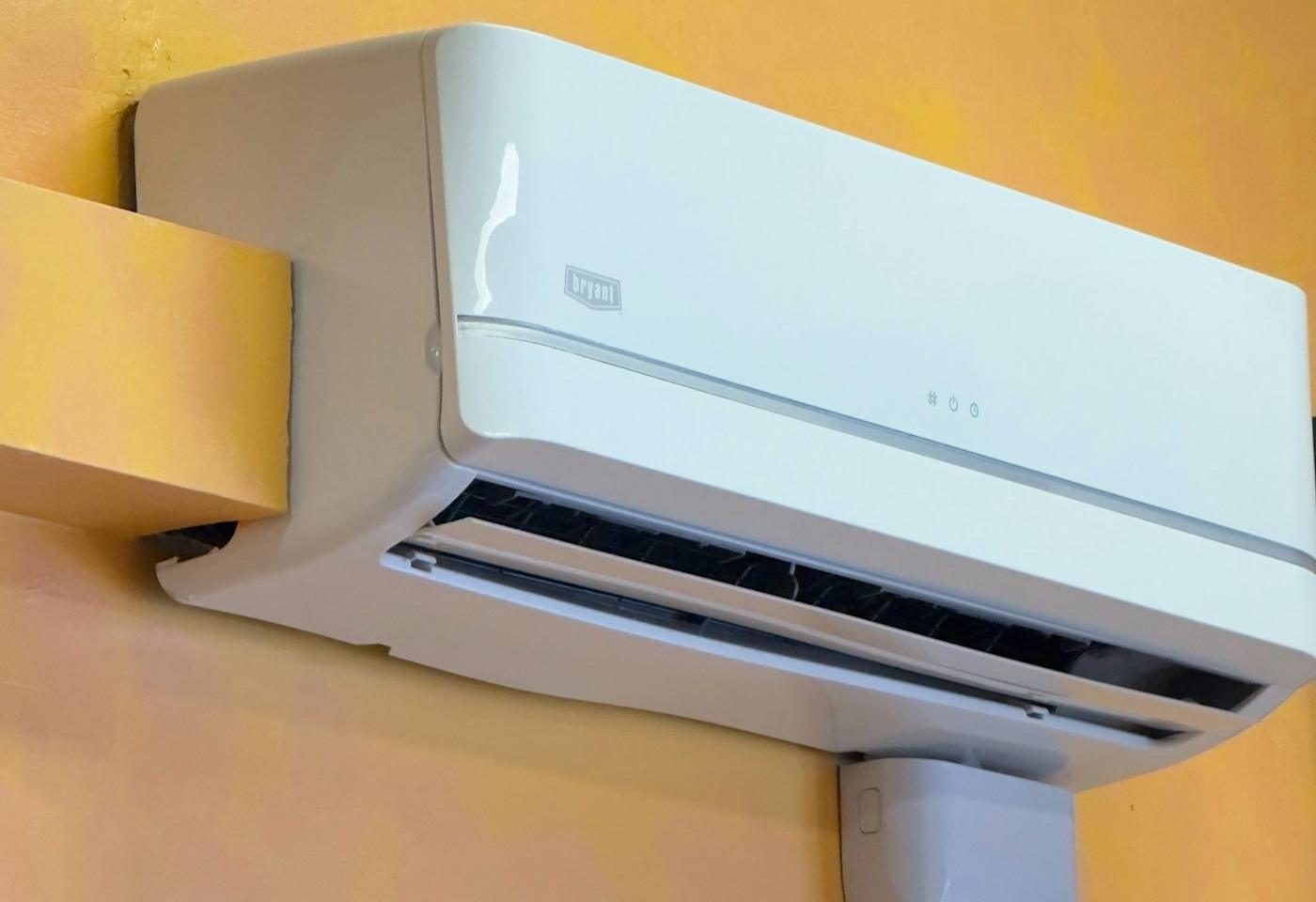 A wall-mounted air-conditioning unit on a yellow wall